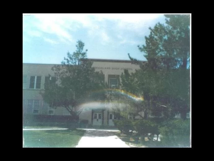 A rainbow and cloud-like anomaly appears in front of the high school in this old picture.